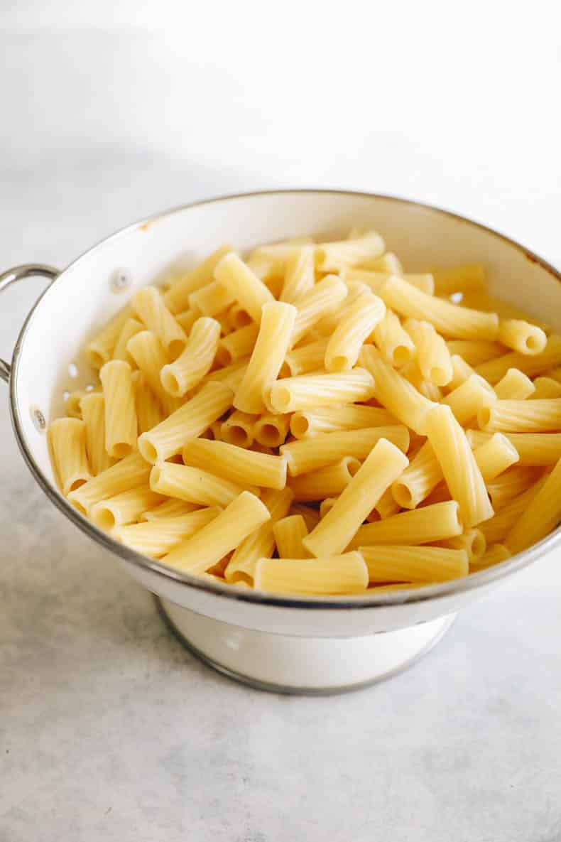 cooked and strained rigatoni in a white colander.